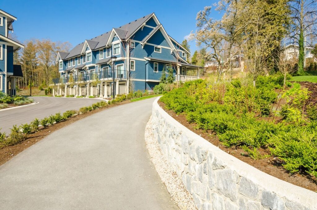 Suburban apartment complex with a clean driveway bordered by modern retaining walls.