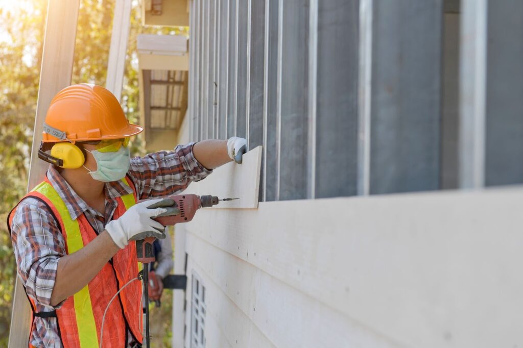 A siding contractor fitting siding panels on a home under construction.