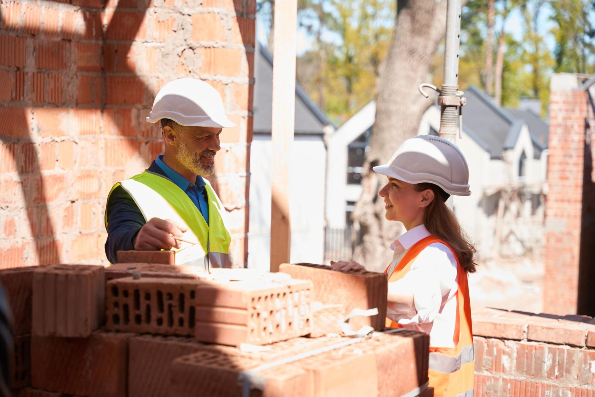 Experienced masonry contractors discussing the project near a pile of construction bricks.